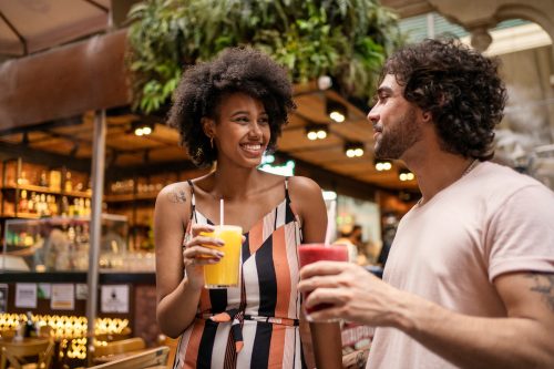 Young couple drinking juice in a market, looking lovingly at each other