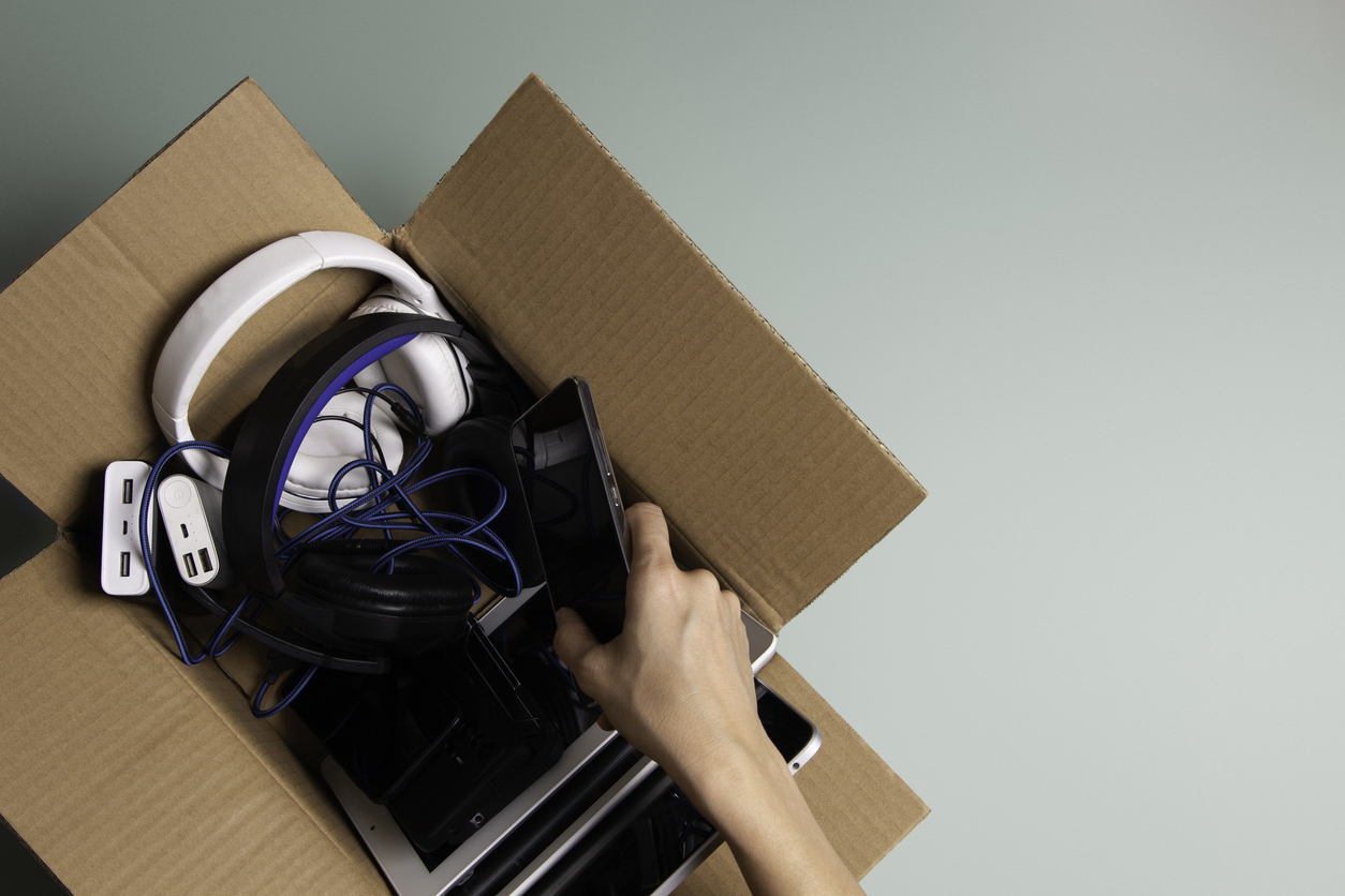 cardboard box of electronics with hand reaching in to remove a cellphone