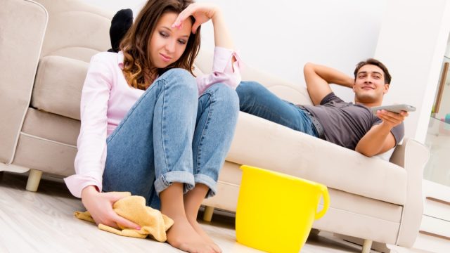 Man Watching TV While Woman Cleans