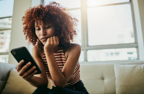 Woman, phone and home sofa while online for communication on social media mobile app chat. Bored person with smartphone typing email, blog post or search on internet waiting on slow wifi connection