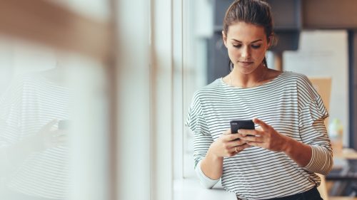 woman at work looking at her phone reading break up texts