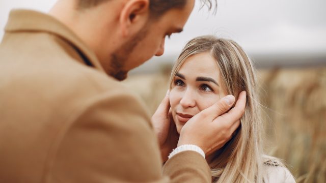 man being affectionate with his girlfriend in a field