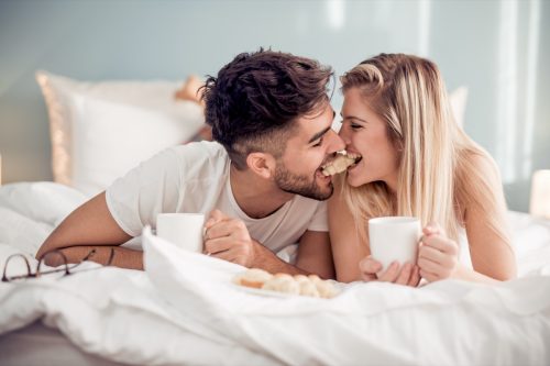 Man and woman having breakfast in bed