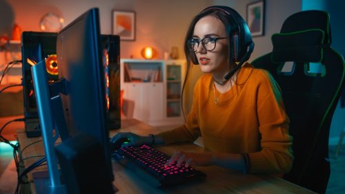 young woman wearing glasses and headseat, playing games online with gaming setup