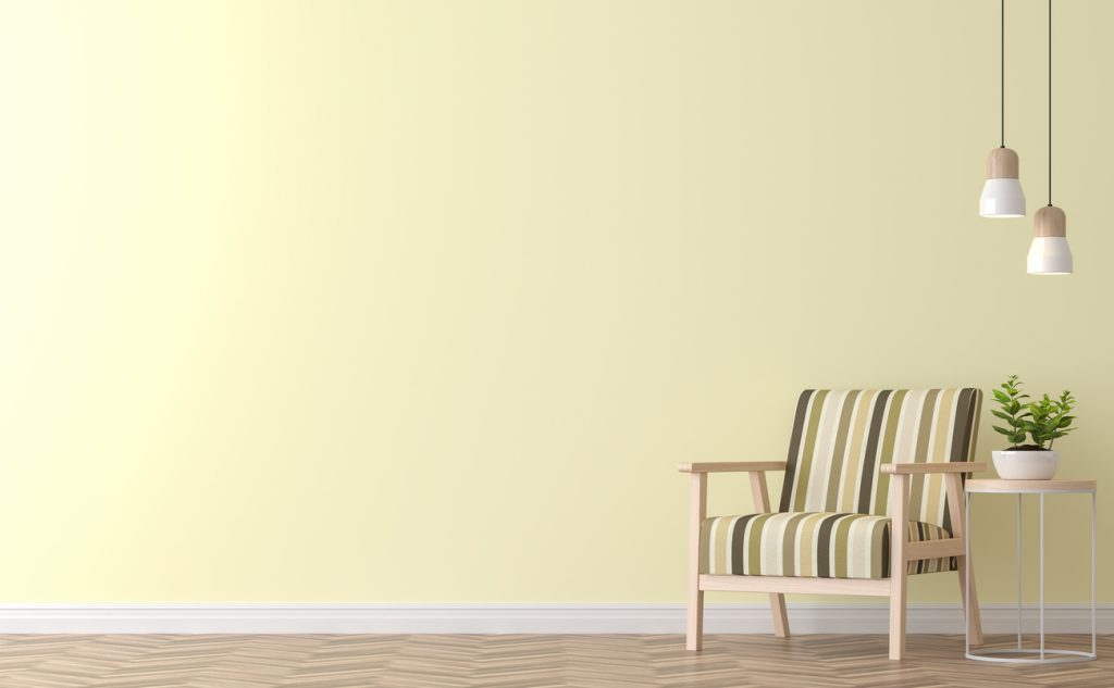 striped chair, side table with a plant, and two hanging lamps against gentle yellow wall