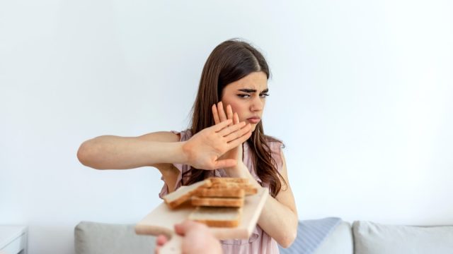 Cropped shot of a young woman on a gluten free diet is saying no thanks to white bread. Woman refusing to eat white bread.