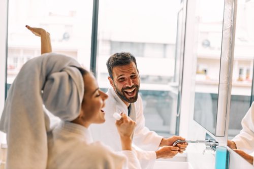 man laughing in a bathroom in response to a woman's funny good morning messages to him