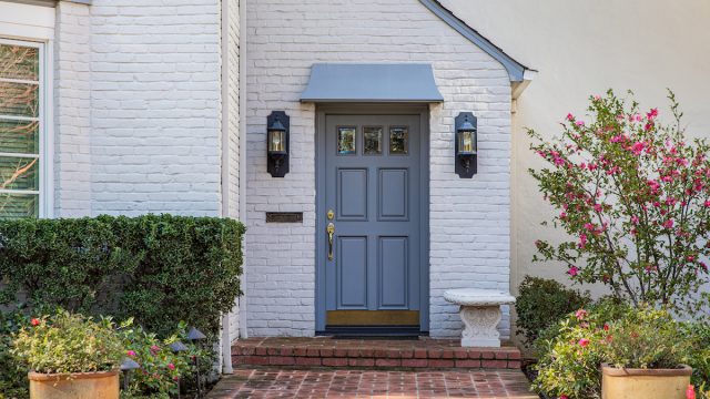 Blue front door of traditional style home with brick entry and white brick exterior.