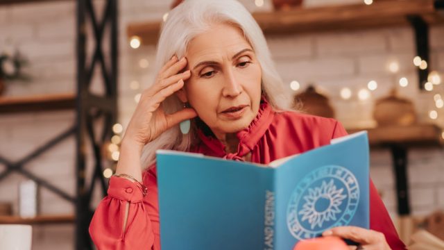 older woman reading astrology book