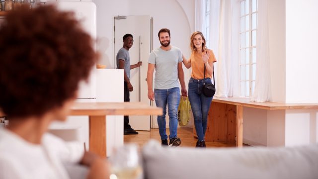 Couple Greeting Friends Arriving For Dinner Party At Home