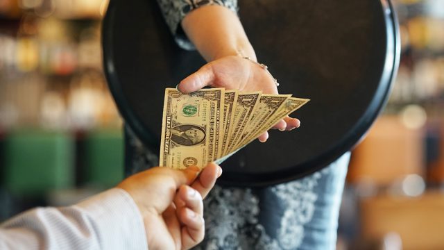 Close up of a waitress accepting cash from a customer