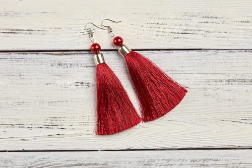 red tassel earrings on white wood background