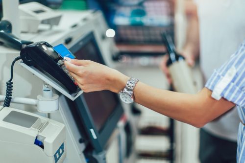 Woman tapping to pay at grocery checkout