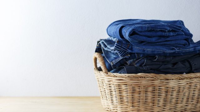 Clothes and jeans in a laundry basket on Wood floor