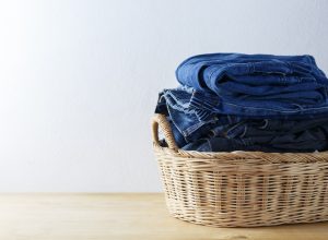 Clothes and jeans in a laundry basket on Wood floor
