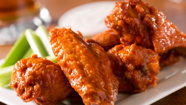A plate of buffalo style chicken wings with celery and blue cheese with a beer on a bar or restaurant table. Please see my portfolio for other food and drink images.