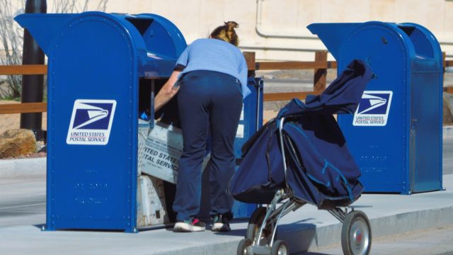April 04 2023: A USPS postal worker collects the outgoing mail at a drive thru drop off box.