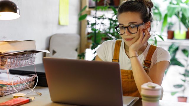 Young woman in glasses using laptop sitting at desk