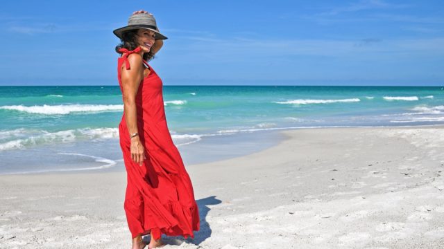 Beautiful Mature Woman Wearing a Red Summer Dress on the Beach