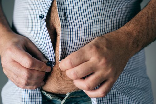 overweight man trying to button his shirt; dad bod