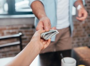 Close up of someone handing a person dollar bills