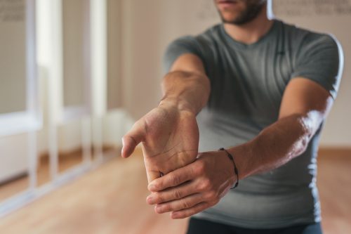 Man stretching his hand and forearm before a workout