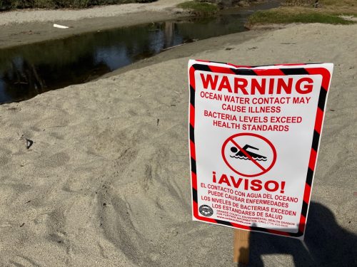 beach sign warns of health risk due to polluted water
