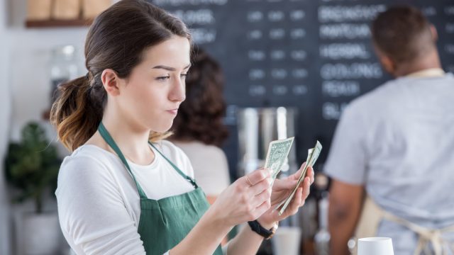 A server counting their tips with a disappointed look on their face