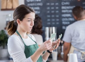 A server counting their tips with a disappointed look on their face