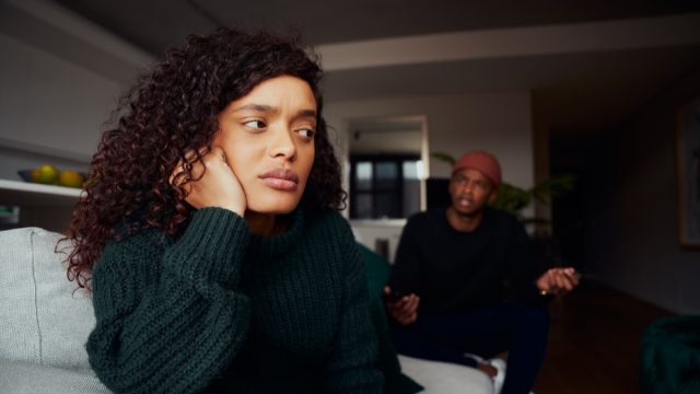 female upset with boyfriend while fighting on the sofa in modern apartment