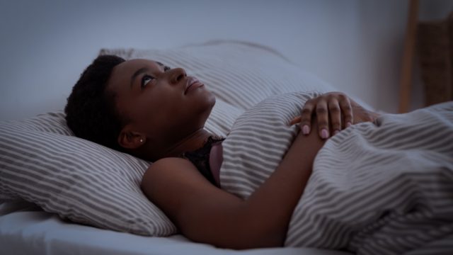 young woman lying in bed awake at night