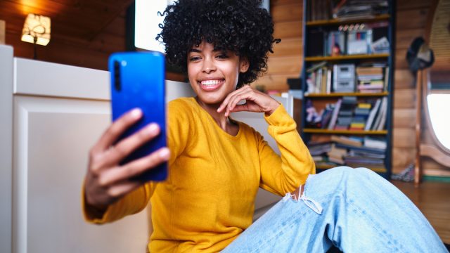 Woman sitting on the ground taking pictures of herself.