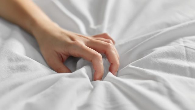 Woman's hand clutching bedsheets
