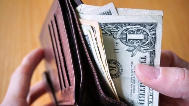 A close up of someone taking a dollar bill out of a wallet