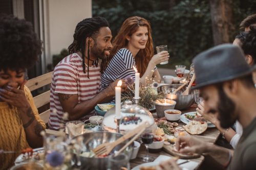 group of friends have dinner party on porch, everyone enjoy in food, drinking and smiling.