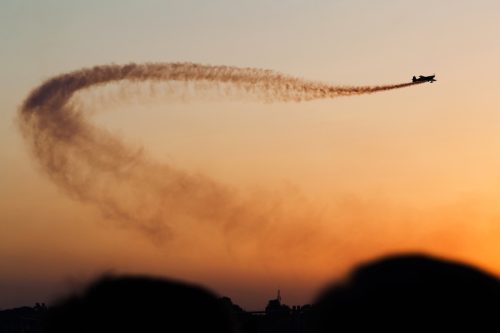 Plane leaving dark smoke trail over sky