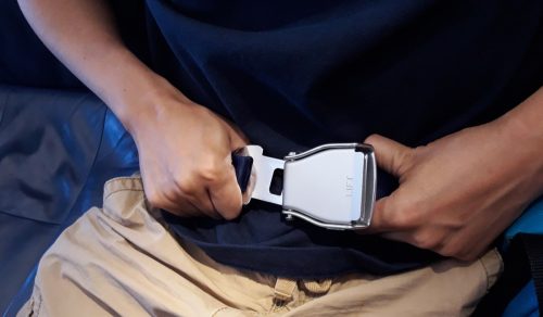 passenger prepares to fasten seat belt before airplane taking off.