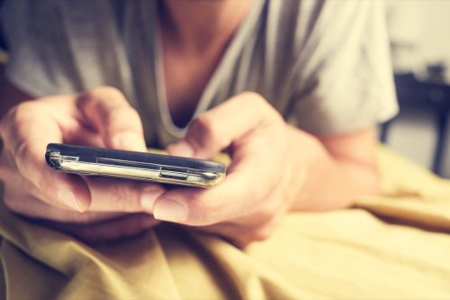 man texting from bed
