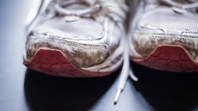 Old dirty sneakers close up, selective focus, desaturated colors.
