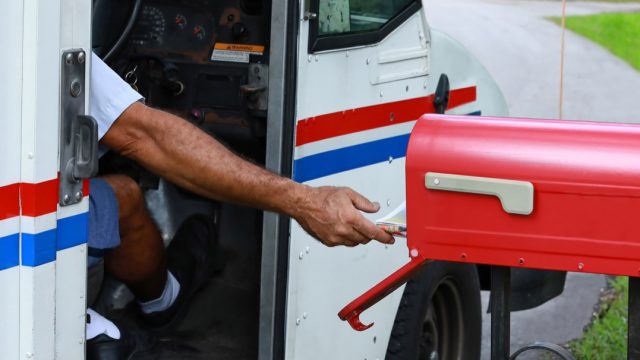 Mail man reaches out of his truck to deliver mail. Official mail delivery slowdown started on October 1, 2021, as seen on October 2, 2021.