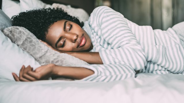 close up of a pretty woman with curly hair sleeping in bed closed eyes