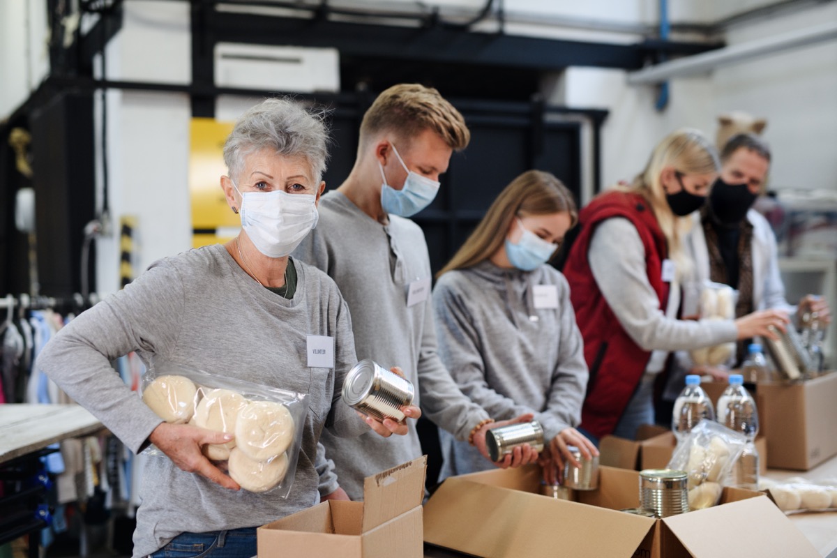 Group of volunteers in community charity donation center, food bank and coronavirus concept.
