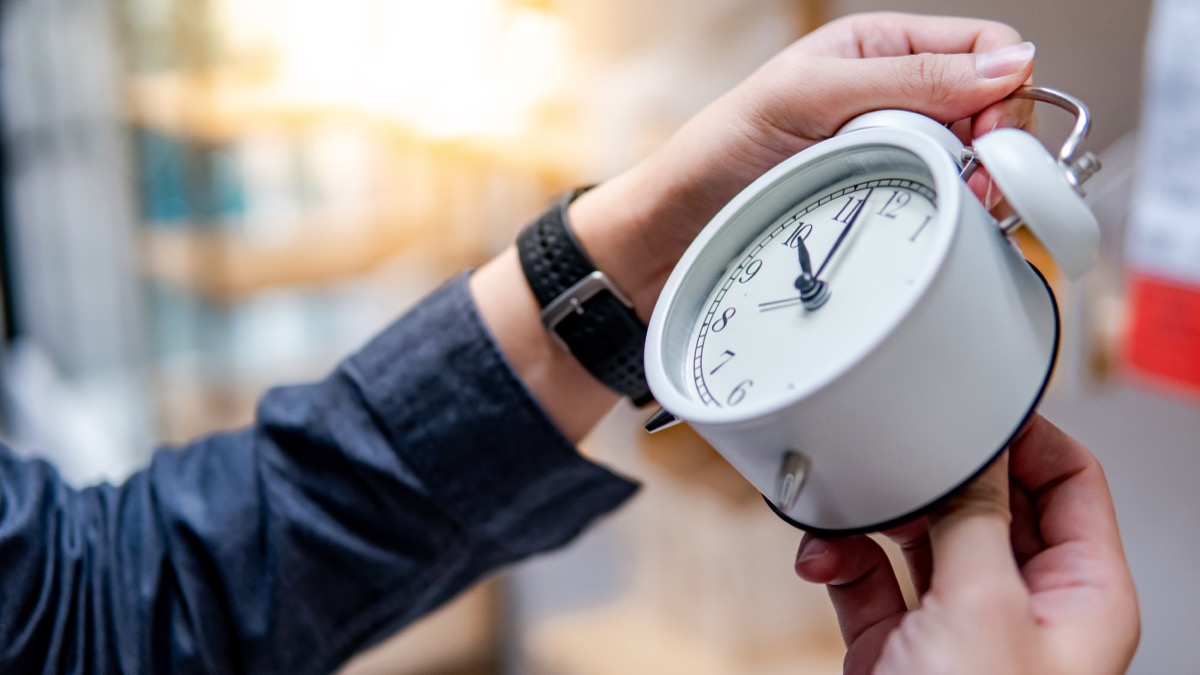 Hands holding clock and changing time