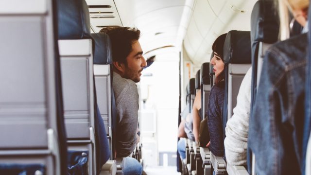 Interior of airplane with people sitting on seats and talking. Friends traveling by flight.