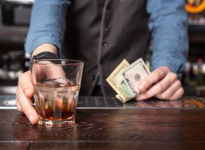 Barman giving whiskey glass with booze - closeup.