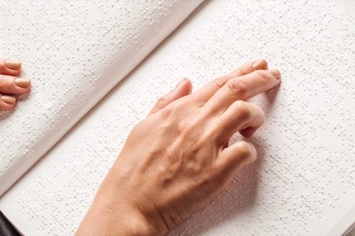 Blind woman read book written in Braille.