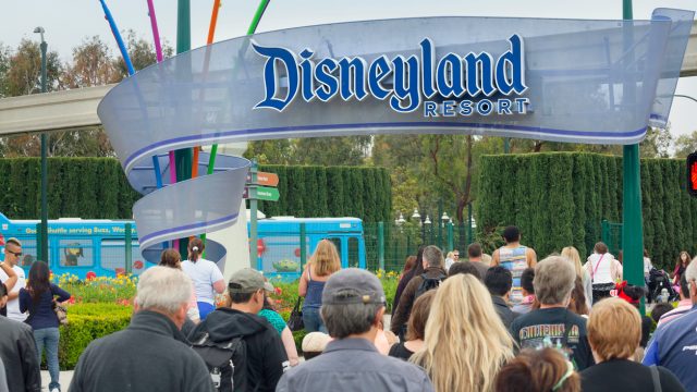 A crowd of people walking in through the entrance to Disneyland park