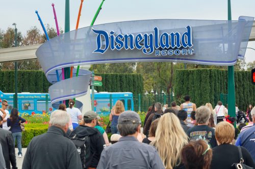 A crowd of people walking in through the entrance to Disneyland park