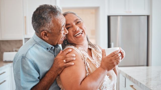 Man and woman standing in kitchen and laughing