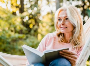 Beautiful,Senior,Blonde,Woman,Reading,Book,And,Sitting,In,Hammock